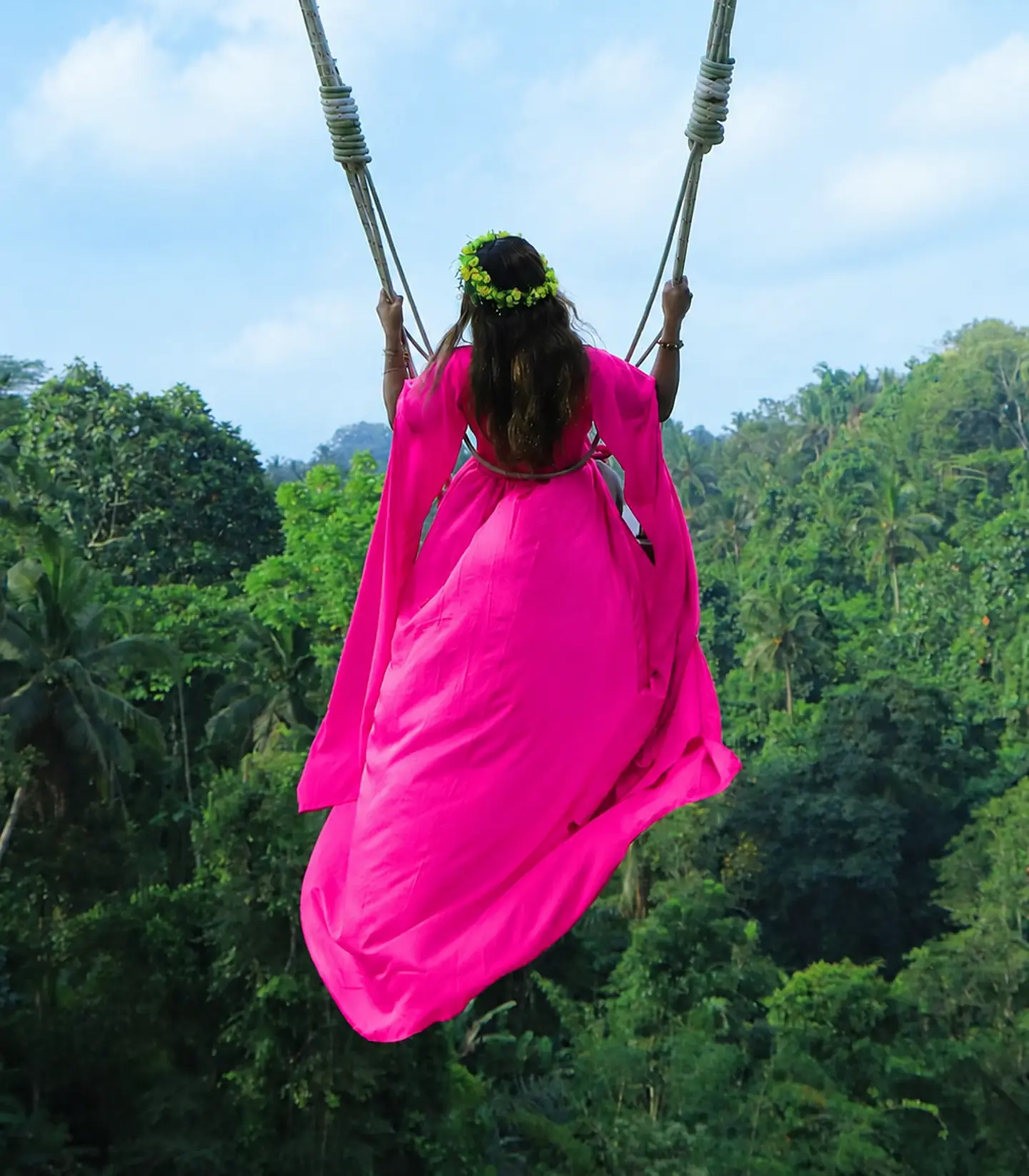 Nicci Reynolds overlooking a tropical landscape in a flowing fuchsia dress